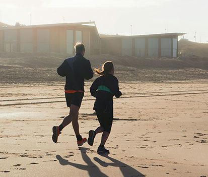 man and woman running on a beach