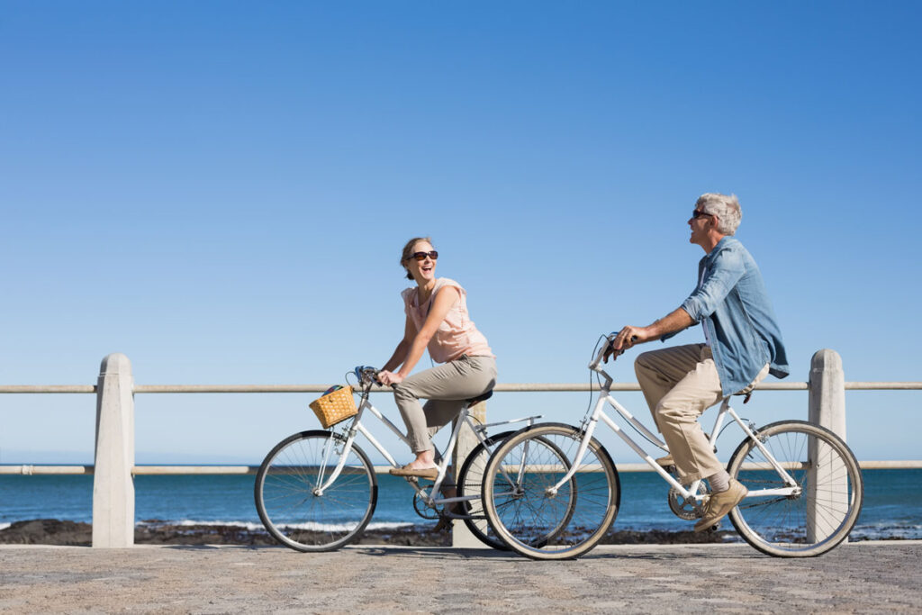 couple cycling by the beach and laughing